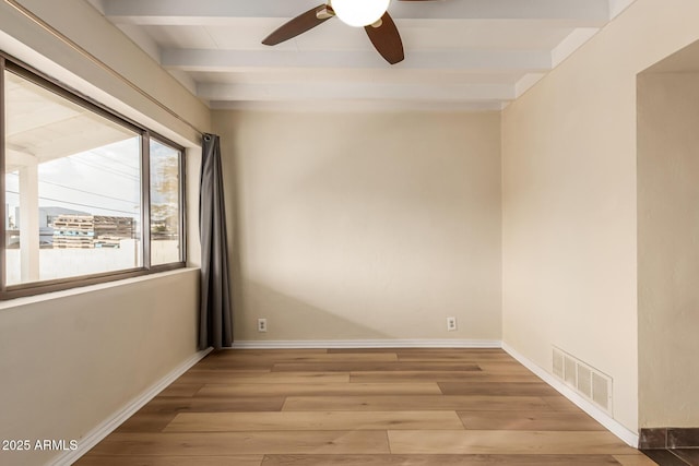 empty room featuring beam ceiling, light hardwood / wood-style flooring, and ceiling fan