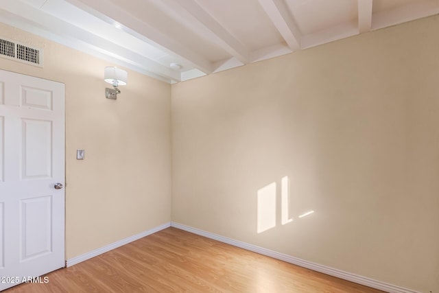 unfurnished room featuring beamed ceiling and light wood-type flooring