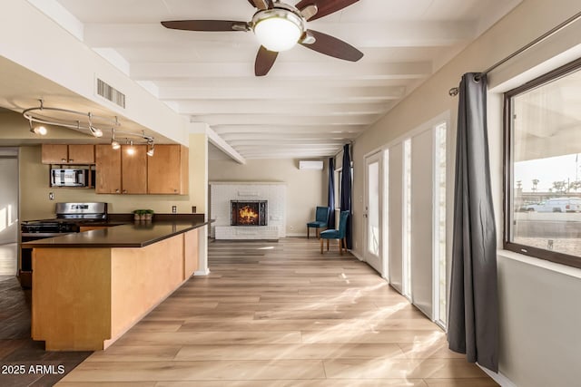 kitchen featuring a breakfast bar area, a brick fireplace, appliances with stainless steel finishes, kitchen peninsula, and beam ceiling