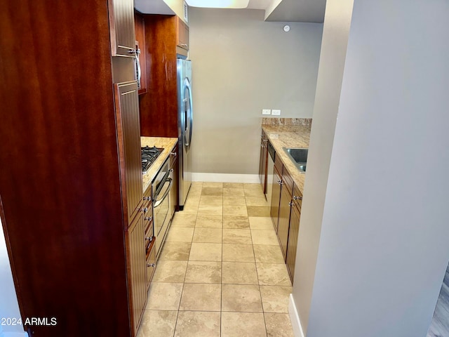 kitchen featuring light stone countertops, sink, light tile patterned floors, and stainless steel appliances