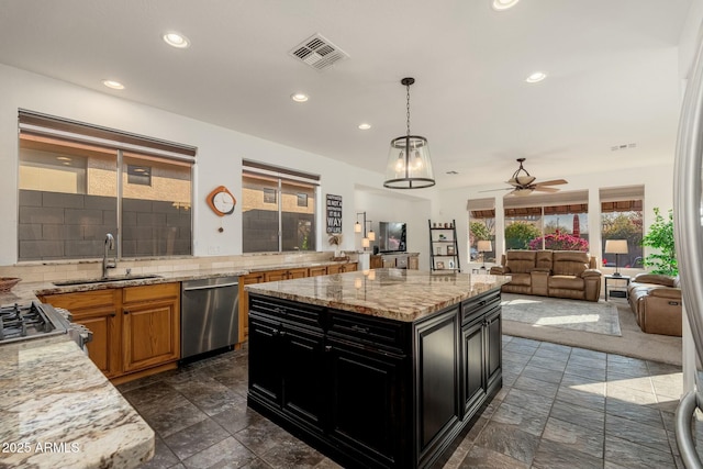 kitchen featuring sink, dishwasher, a kitchen island, light stone countertops, and backsplash