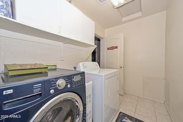 laundry area with cabinets, light tile patterned floors, and washing machine and dryer