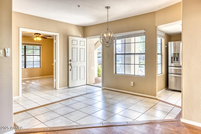 tiled foyer featuring a chandelier, baseboards, and ceiling fan
