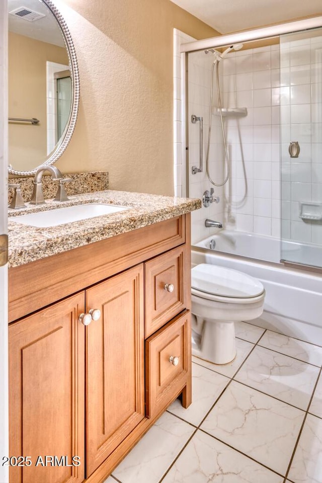 bathroom with a textured wall, vanity, toilet, bath / shower combo with glass door, and marble finish floors