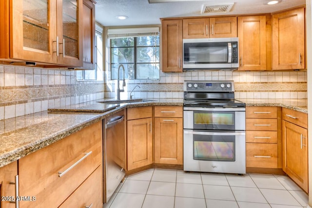 kitchen featuring appliances with stainless steel finishes, a sink, brown cabinets, and recessed lighting