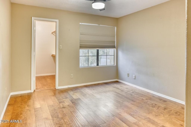 empty room with ceiling fan, wood finished floors, and baseboards
