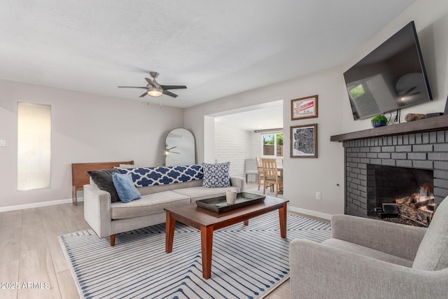 7727 E 4th St, Scottsdale, AZ 85251 - living area featuring a brick fireplace, ceiling fan, baseboards, and light wood-style floors