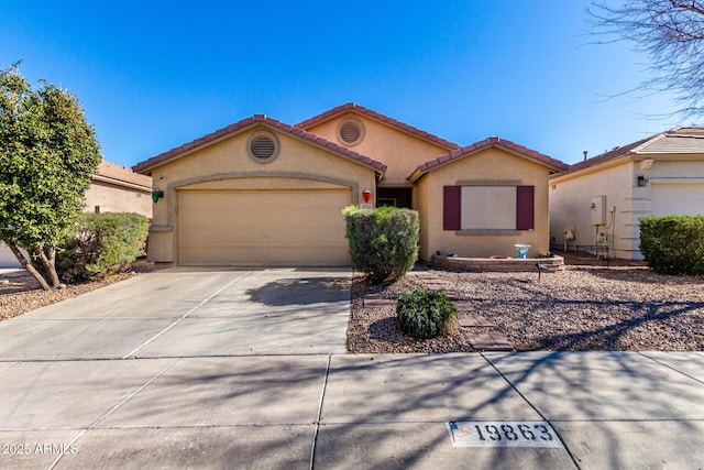 view of front of home featuring concrete driveway, a tile roof, an attached garage, and stucco siding