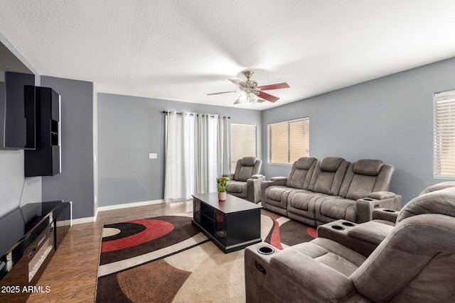 living room featuring a textured ceiling, baseboards, a ceiling fan, and wood finished floors