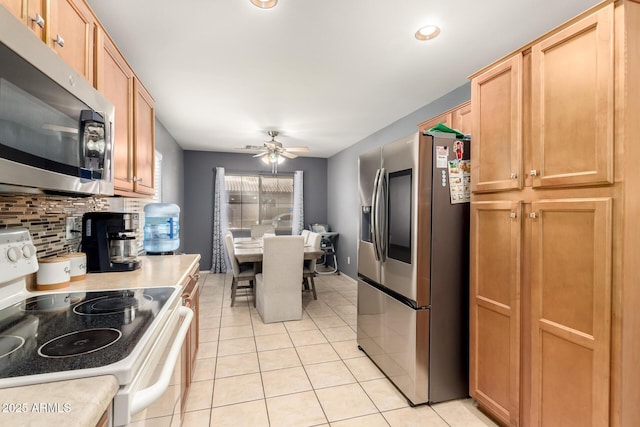 kitchen with light tile patterned floors, ceiling fan, light countertops, appliances with stainless steel finishes, and decorative backsplash