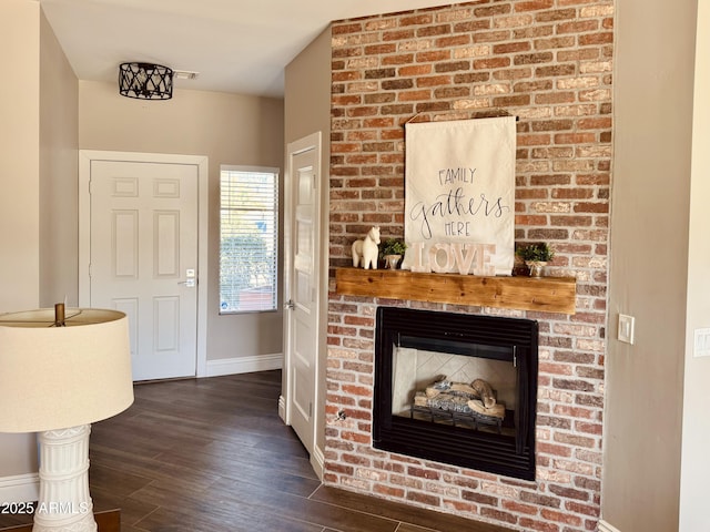 living area featuring a brick fireplace, wood finished floors, and baseboards