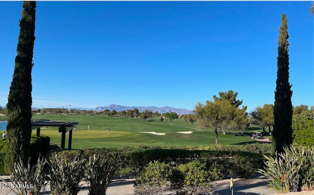 view of home's community with view of golf course, a yard, and a mountain view