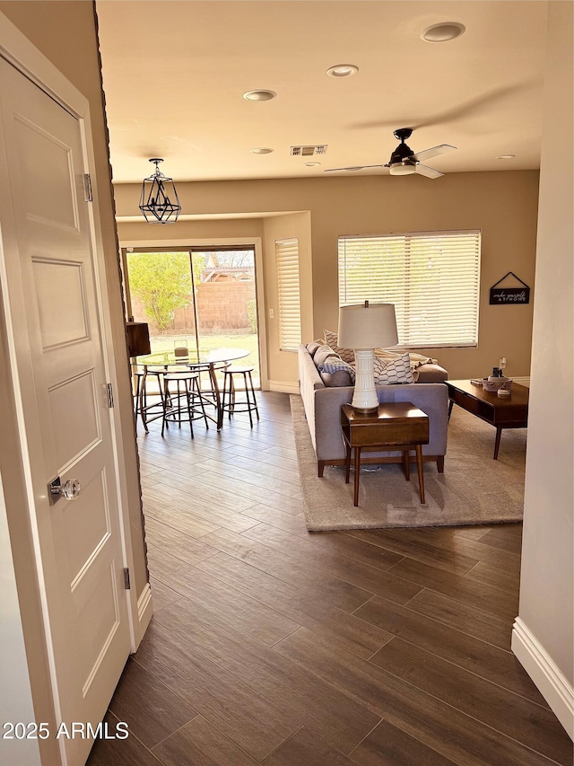 living room with baseboards, visible vents, a ceiling fan, dark wood-type flooring, and recessed lighting