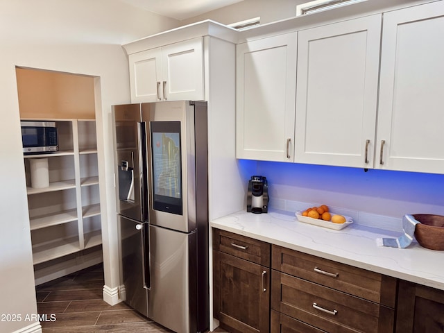 kitchen featuring stainless steel appliances, light stone countertops, dark brown cabinets, and white cabinets