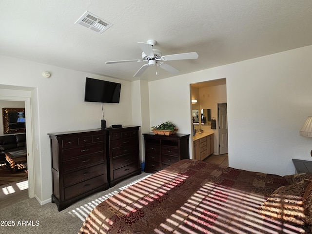 bedroom featuring a textured ceiling, connected bathroom, light carpet, visible vents, and a ceiling fan