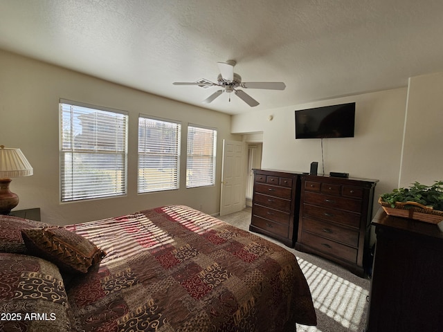 bedroom featuring a ceiling fan, a textured ceiling, and light colored carpet