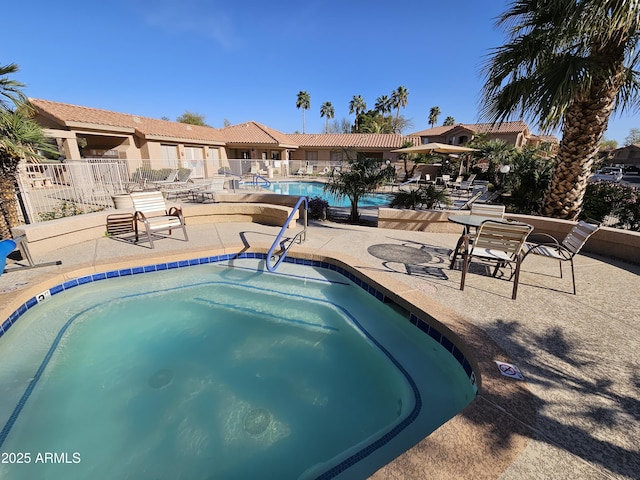 community pool with a patio area and fence