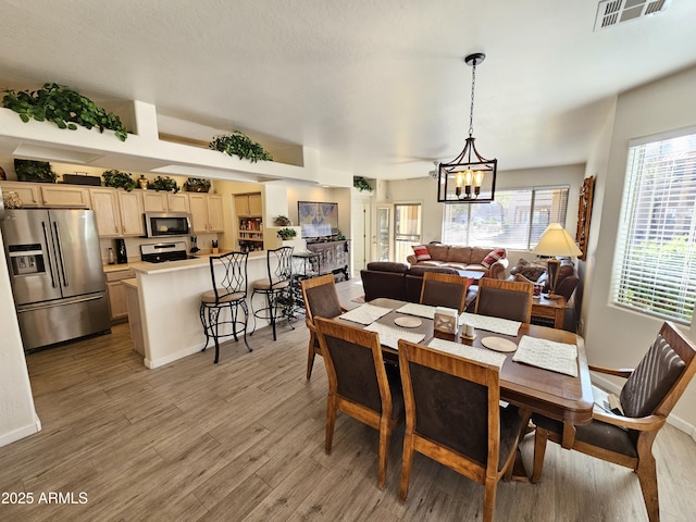 dining room with light wood-style floors, visible vents, baseboards, and an inviting chandelier