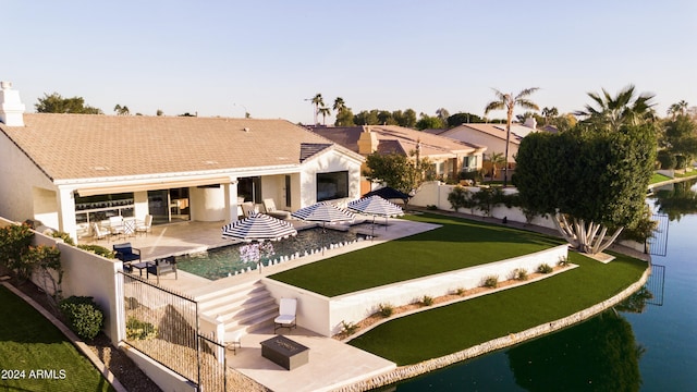 rear view of house with a yard, a patio area, a fire pit, and a water view