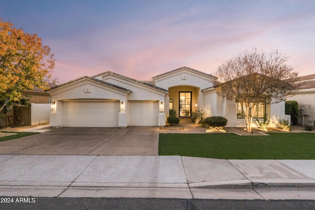 mediterranean / spanish house with a yard and a garage