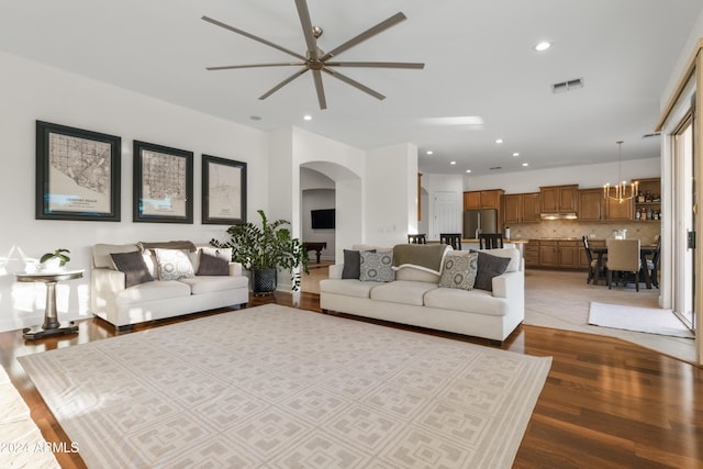 living room with ceiling fan with notable chandelier and wood-type flooring