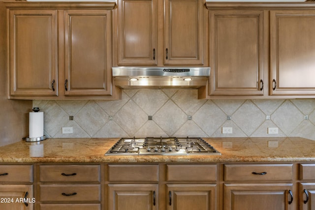 kitchen featuring decorative backsplash, stainless steel gas stovetop, and light stone counters