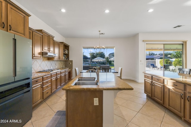 kitchen with sink, backsplash, a center island with sink, a notable chandelier, and appliances with stainless steel finishes