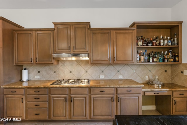 kitchen featuring decorative backsplash, stainless steel gas stovetop, and light stone counters