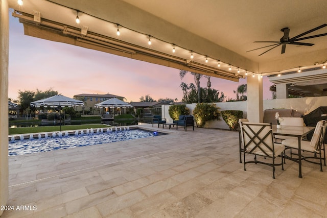 patio terrace at dusk featuring pool water feature and a fenced in pool