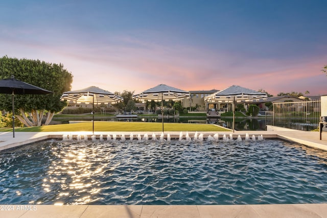 pool at dusk featuring a lawn