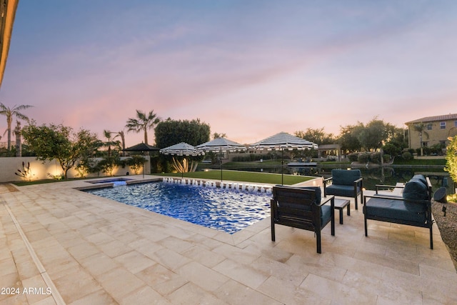 pool at dusk featuring a patio area