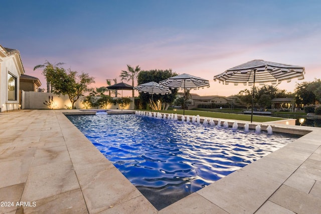 pool at dusk featuring a patio area