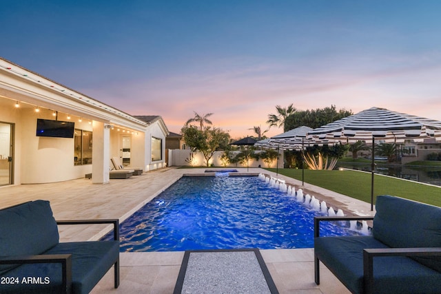 pool at dusk featuring a lawn and a patio area