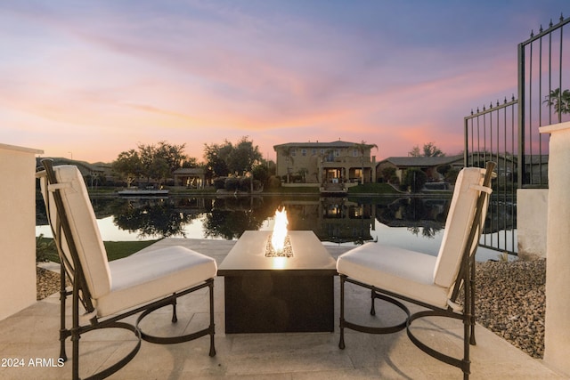 patio terrace at dusk featuring a fire pit and a water view