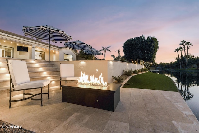 patio terrace at dusk with a water view and an outdoor fire pit