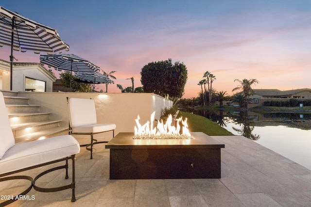 patio terrace at dusk with an outdoor fire pit and a water view