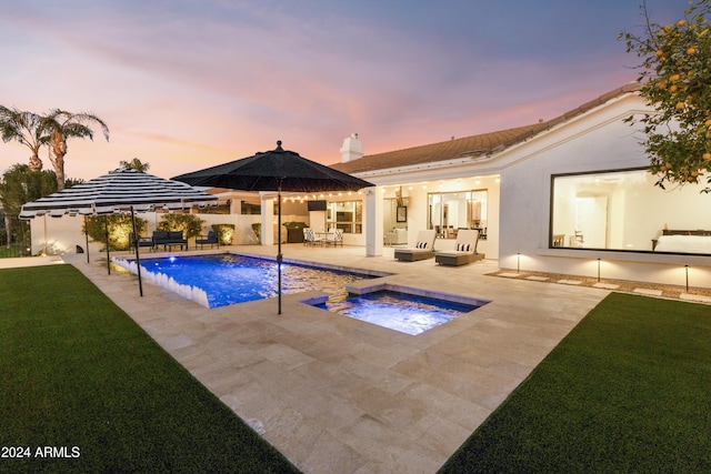 pool at dusk with pool water feature, an outdoor hangout area, an in ground hot tub, a lawn, and a patio