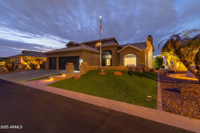 mediterranean / spanish-style home featuring a yard and a garage