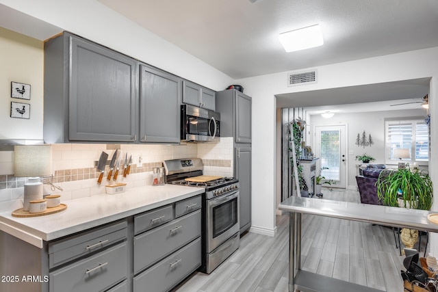 kitchen featuring tasteful backsplash, gray cabinetry, visible vents, and stainless steel appliances