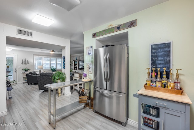 kitchen featuring visible vents, ceiling fan, wood tiled floor, and freestanding refrigerator