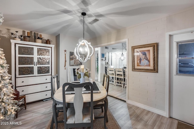 dining space featuring visible vents, light wood-style floors, and a chandelier