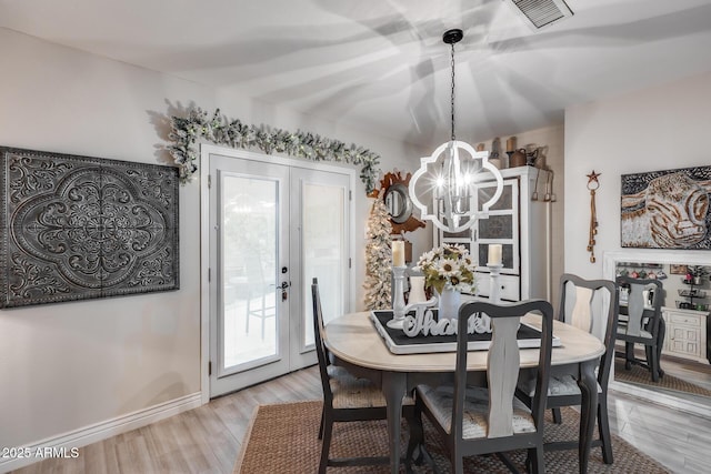 dining room featuring an inviting chandelier, light wood-style flooring, baseboards, and visible vents