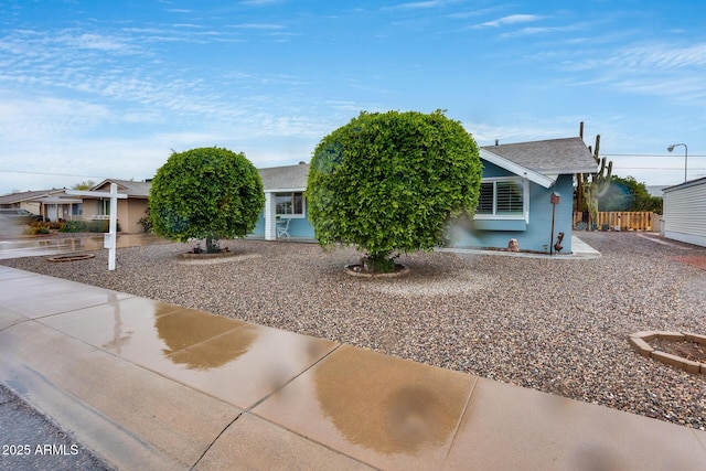 view of property hidden behind natural elements with stucco siding and fence