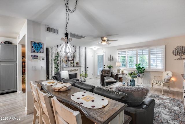 dining area featuring light wood finished floors, visible vents, baseboards, ceiling fan, and a fireplace