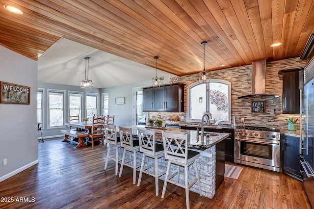 kitchen featuring wooden ceiling, a center island, high end stove, wall chimney exhaust hood, and light stone countertops