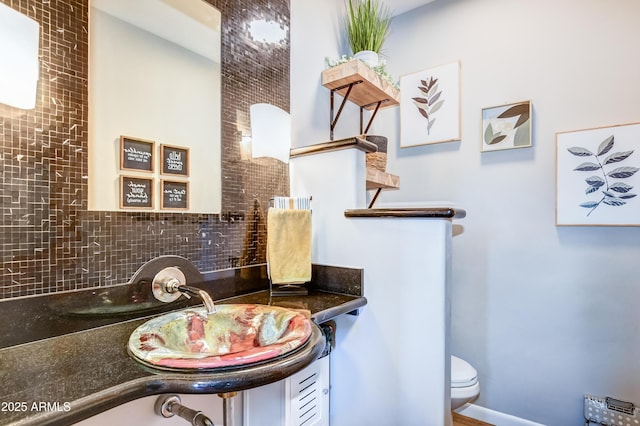 bathroom with toilet, sink, and backsplash