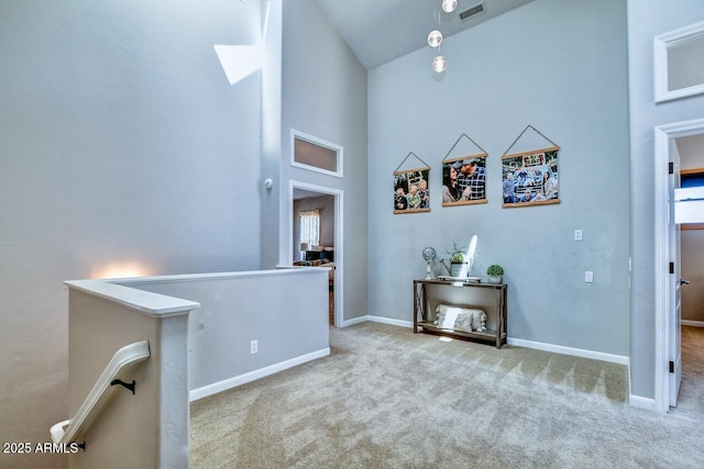 corridor featuring a high ceiling and light colored carpet