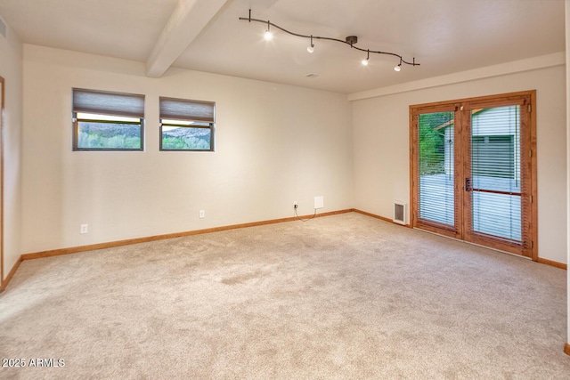 carpeted empty room with beam ceiling, french doors, and plenty of natural light