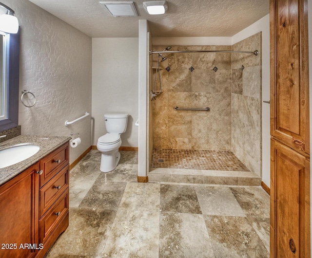 bathroom with a tile shower, vanity, toilet, and a textured ceiling