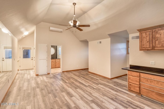 unfurnished living room featuring a wall unit AC, ceiling fan, vaulted ceiling, and light wood-type flooring